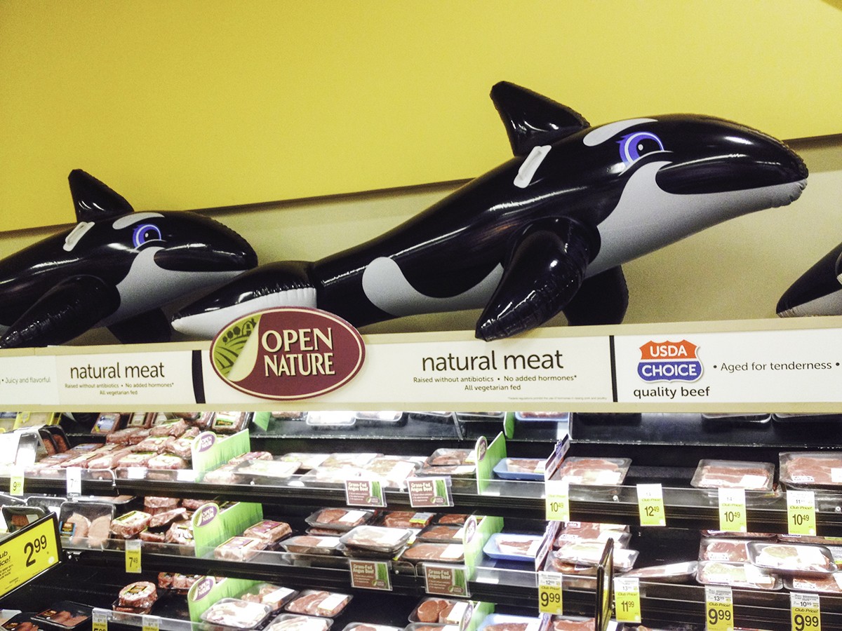 Product merchandising signs for meat below inflatable whale